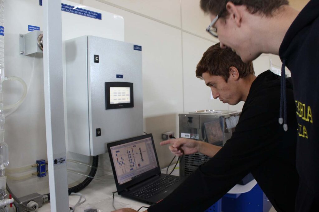 Estudantes de Engenharia Química do IFSULDEMINAS operando a bancada de coluna de destilação pelo painel de controle e supervisório